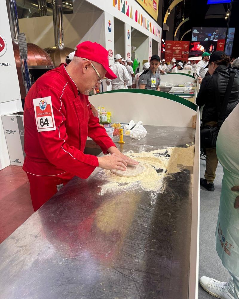 Nicolò Cusumano stende l'impasto al Campionato Mondiale della Pizza, con il numero di gara sul braccio