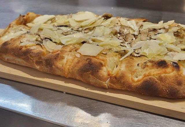 Una pala scrocchiarella con funghi e scaglie di grana, su un tagliere di legno